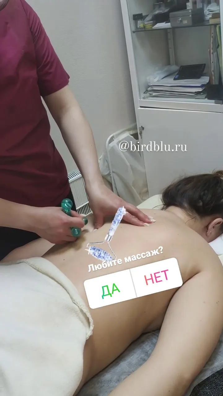 Массаж спины и плеч с использованием массажных палочек, клиент лежит лицом вниз, мастер прорабатывает верхнюю часть спины