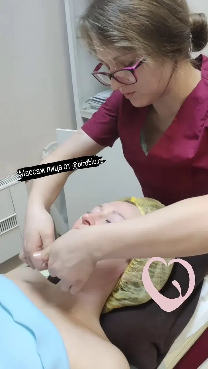 Специалист выполняет массаж лица пациентке на кушетке в клиническом кабинете