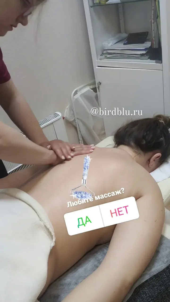 Массажист прорабатывает спину лежащего человека с использованием небольших электродных накладок